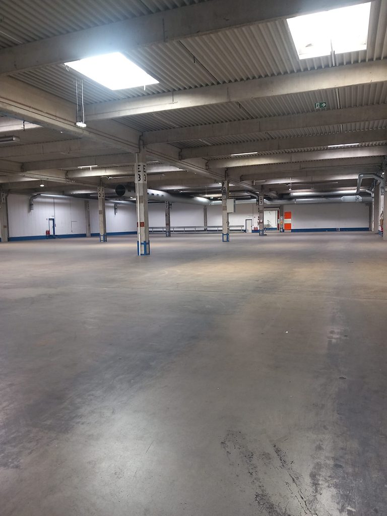 Gereinigte Lagerhalle mit Betonboden und nummerierten Stützen, Hallenreinigung bei Grammer