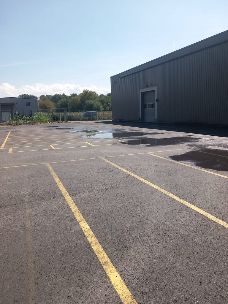 Gereinigter Parkplatz mit gelben Markierungen vor der Lagerhalle bei Grammer