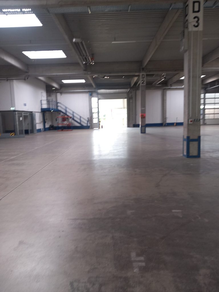 Saubere Lagerhalle mit Betonboden, Stützen und Treppe, Industriereinigung bei Grammer