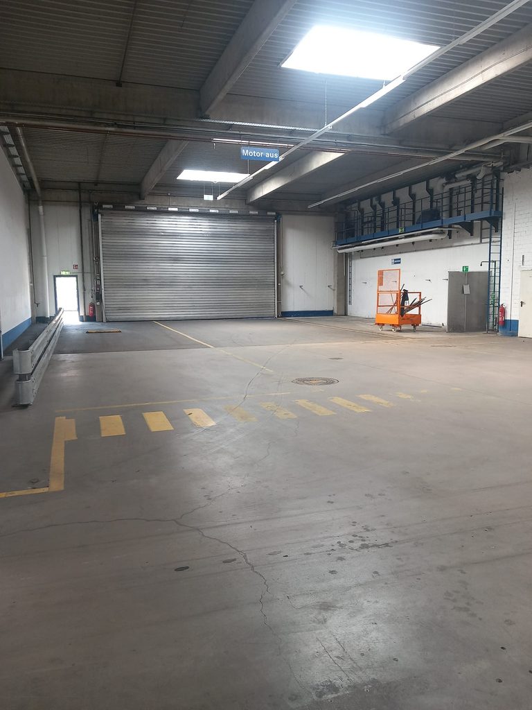 Gereinigte Lagerhalle mit Rolltor und gelben Markierungen, Hallenreinigung bei Grammer
