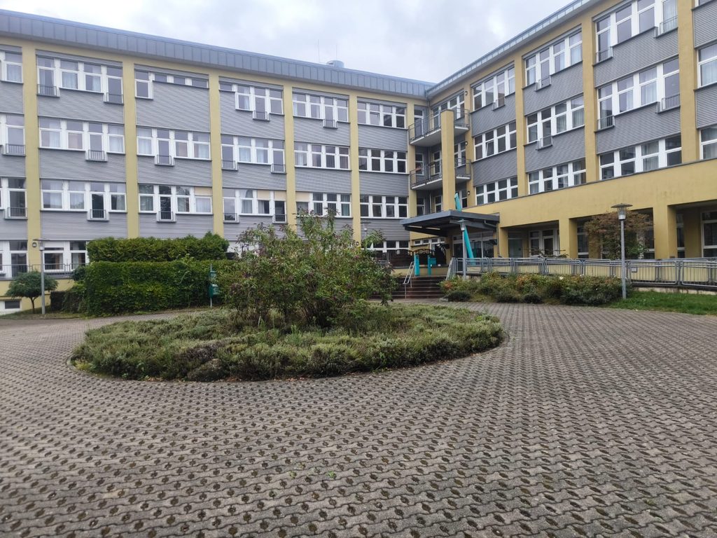 Gepflegter Innenhof mit Rundbeet vor dem Haupteingang von Kursana, Grünanlagenpflege